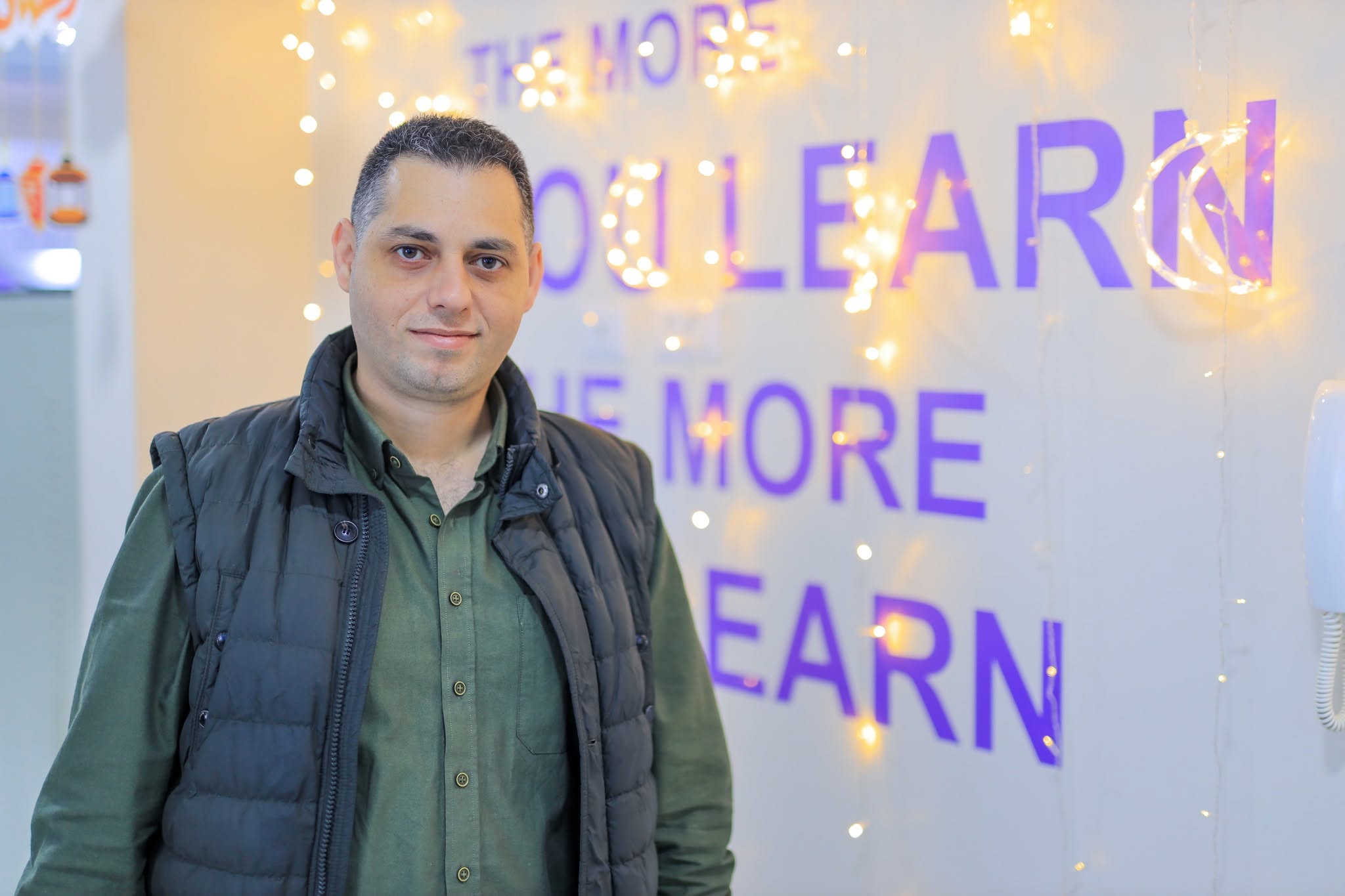 Ahmed Abushaban standing beside a learning-themed display